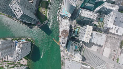 Top-down-ascending-footage-of-futuristic-city-with-high-rise-buildings.-Boats-passing-by-skyscrapers-on-water-surface.-Miami,-USA