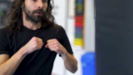 Man-punching-and-kicking-a-striking-bag-in-a-martial-arts-school