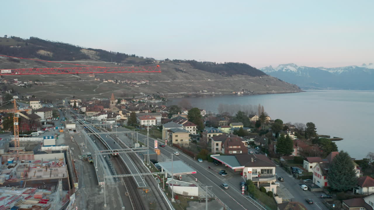 드론이 건설 크레인을 지나 비행하며 작은 스위스 마을을 드러냄
