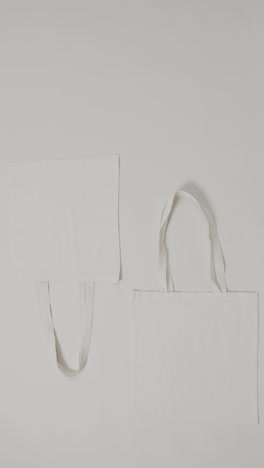 vertical video of white bags on grey background, copy space, slow motion