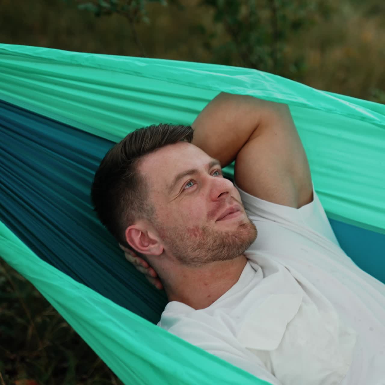 Positive relaxed man lies swinging in the hammock. Good time spending in the nature in summer