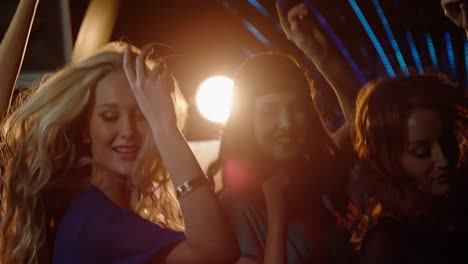 group of smiling friends dancing on dance floor