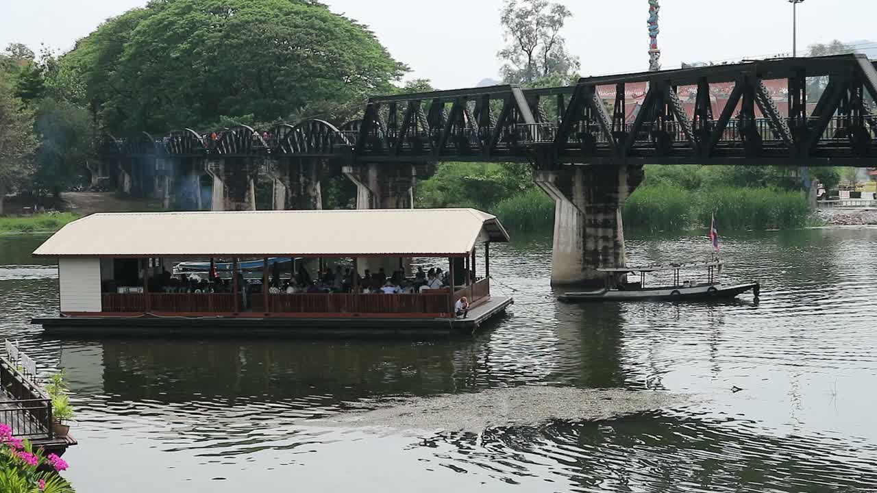 hd ferry con turistas que viajan bajo el puente del río kwai en kanchanaburi, tailandia