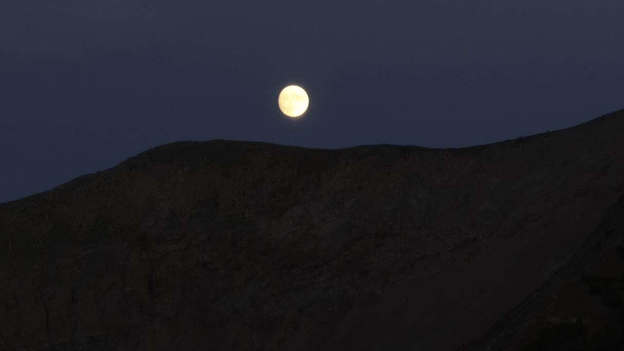 보름달은 밤에 콜로라도 로키 산맥의 능선 뒤에 떨어진다