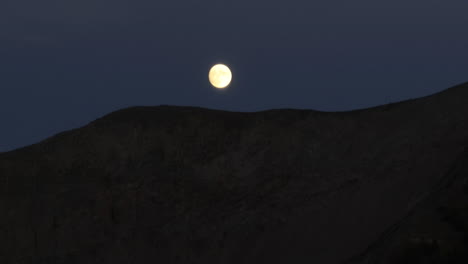 A-full-moon-falls-behind-a-ridge-line-in-the-Colorado-Rockies-at-night