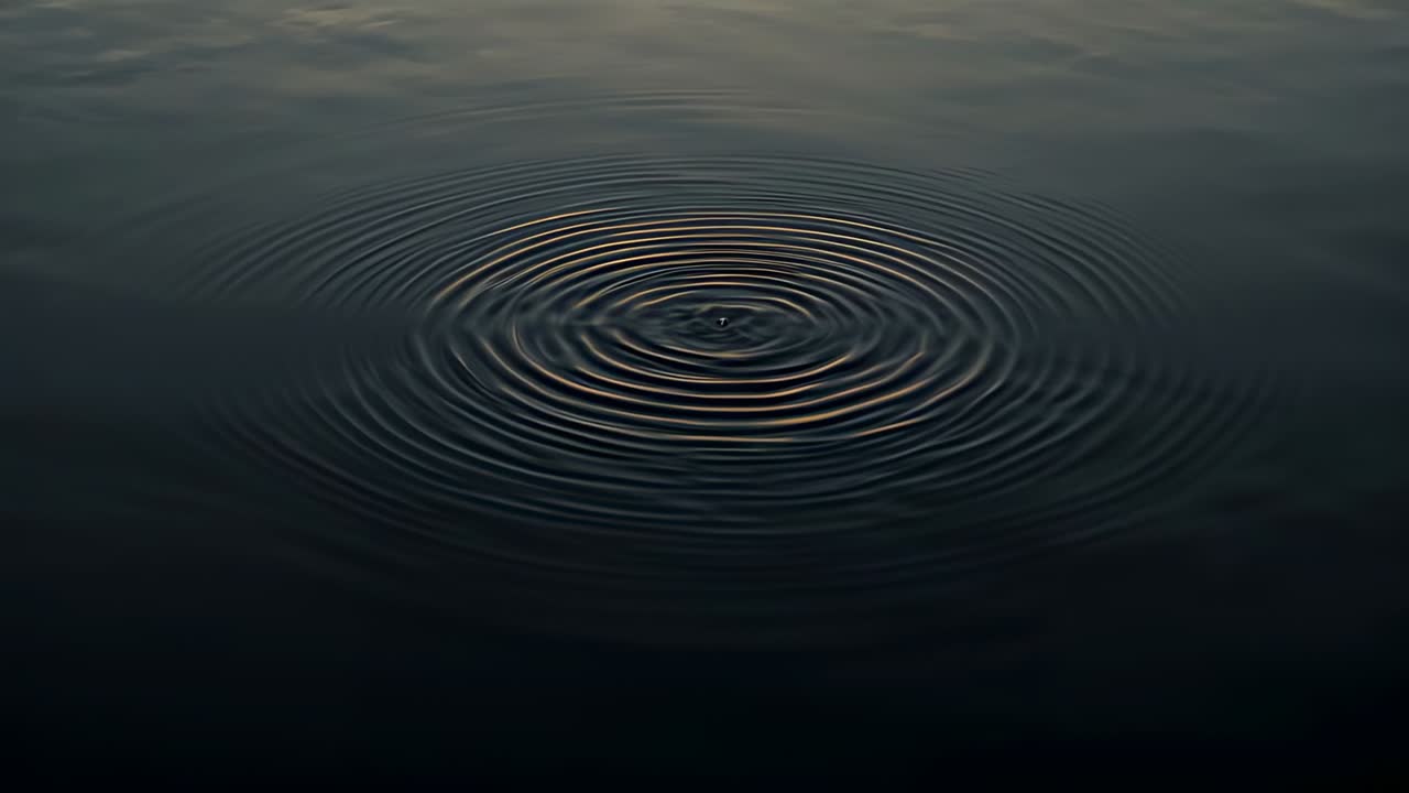 Cirkulære ringe breder sig ud over en rolig dam fra midten og viser et svagt genskær fra himlen