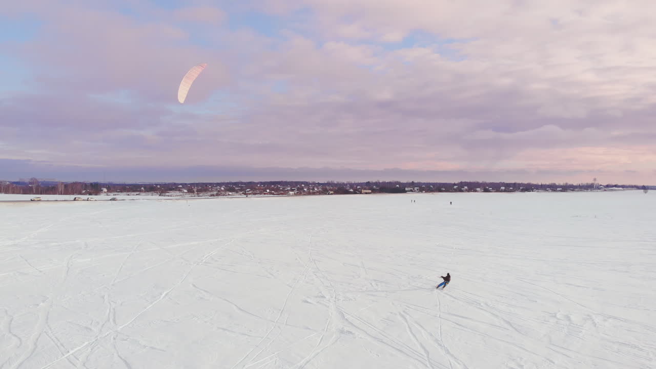 un atleta maschio in abito sportivo sta facendo snowkite sul bellissimo paesaggio invernale.