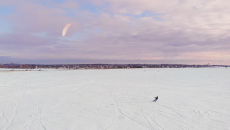 a male athlete in sports outfit is doing snow kiting on beautiful winter landscape.