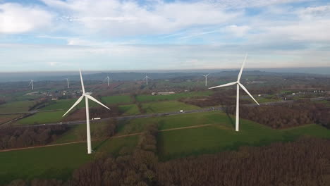 Turbinas-Eólicas-A-Lo-Largo-De-Una-Carretera-Y-Campos-En-Normandía,-Francia.-Toma-Aérea-De-Drones