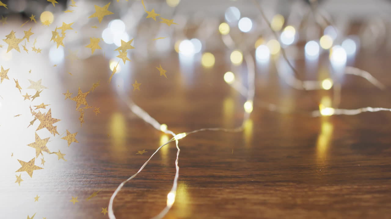 Golden stars animation over string lights on wooden surface