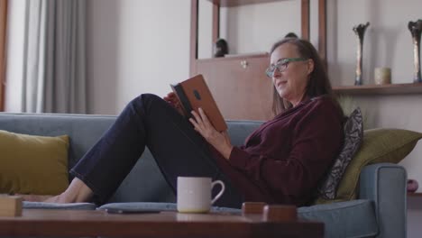 Woman-reading-book-while-sitting-on-the-couch-at-home