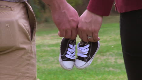 a man and a woman hold little boy's shoes