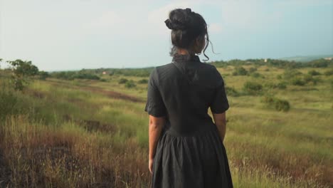 a beautiful woman in a black dress looks sadly into the distance