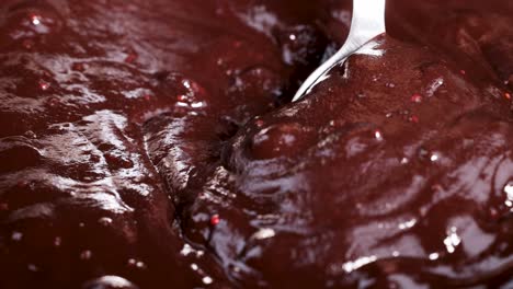 cuchara agitando salpicaduras de colores en una mezcla de chocolate derretido suave