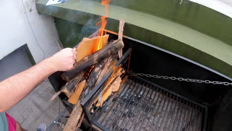 video-of-a-man-preparing-fire-on-a-black-grill-to-cook-roasted-meat-on-a-sunny-day