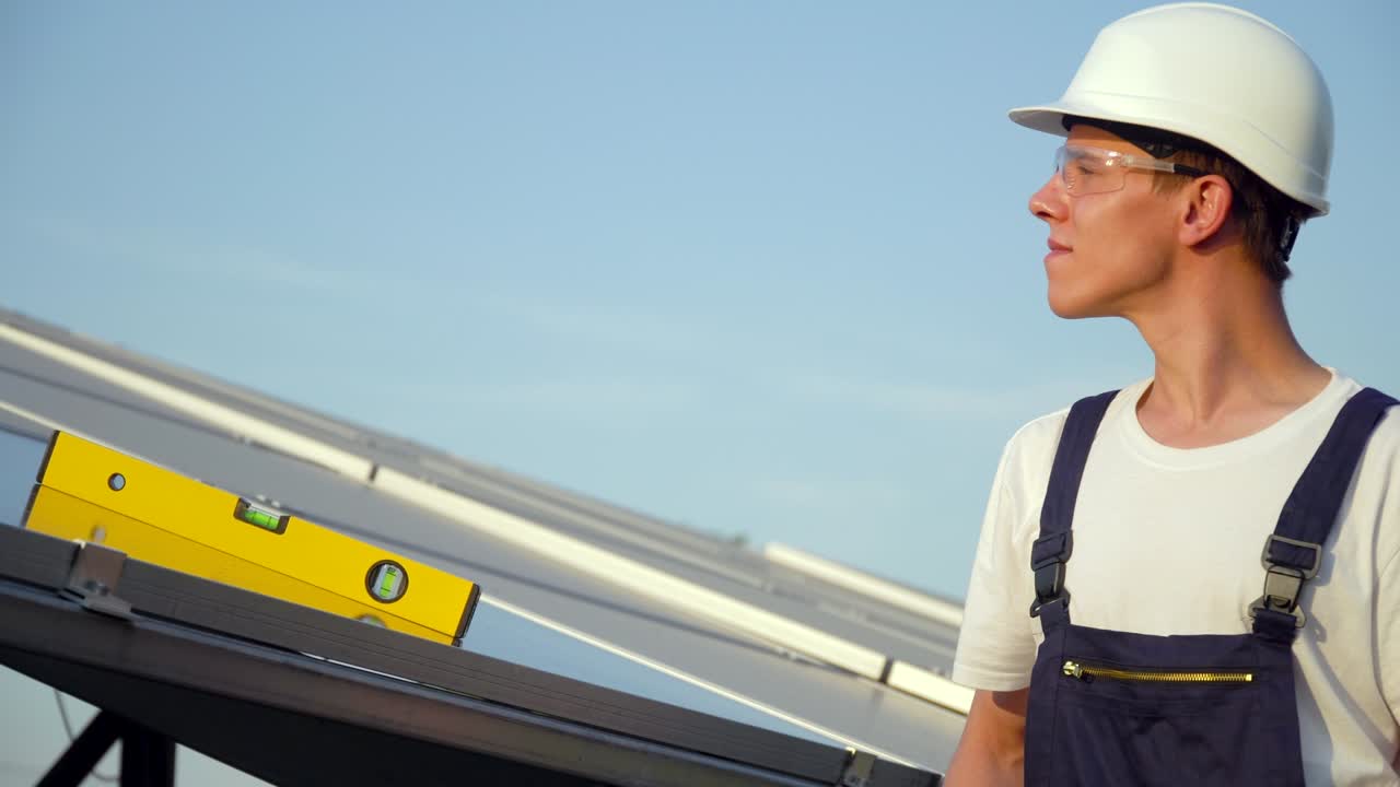 Young enginneer installing new sunny batteries. Worker in a uniform and hardhat installing photovoltaic panels on a solar farm. The future is today. Green energy concept