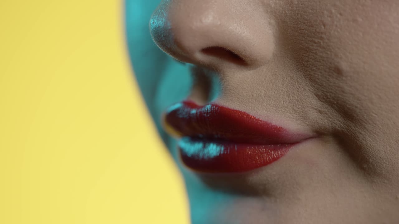 mujer laméndose los labios, lápiz labial rojo, fondo amarillo