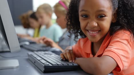 vista lateral escolar afroamericana usando una computadora de escritorio en el escritorio en el aula 4k