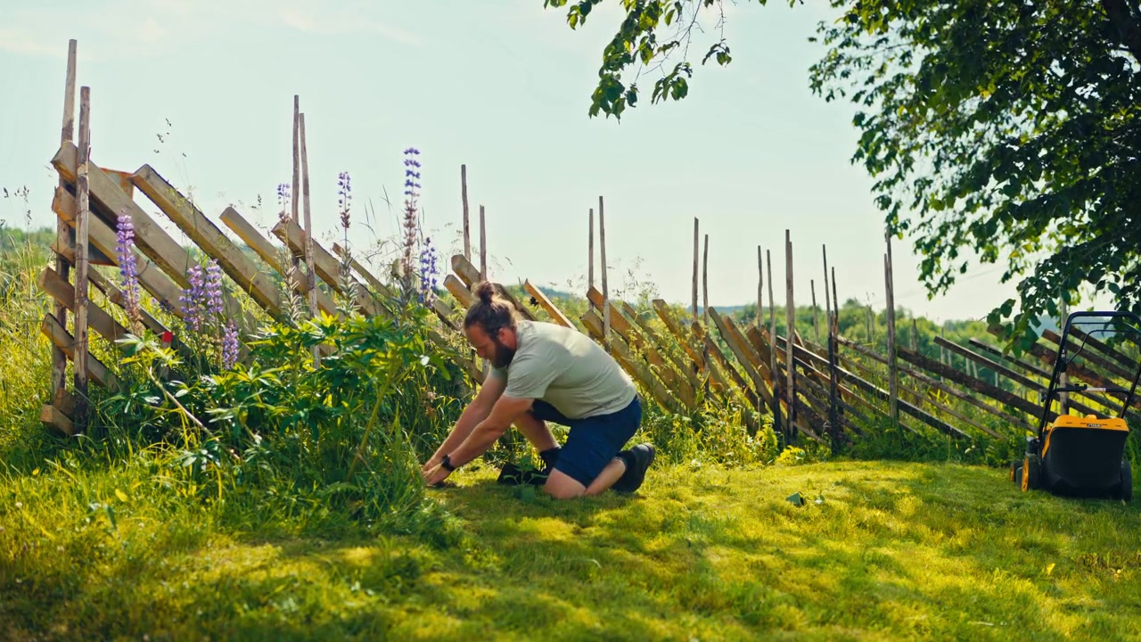 Man digging soil for planting in a rural area in Norway, working outdoors in a green countryside landscape