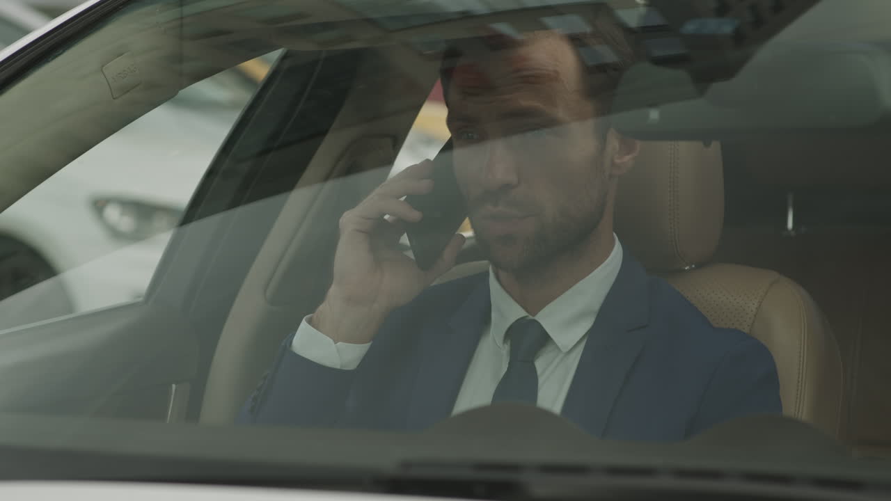 Businessman Talking on Phone in Front Car Seat
