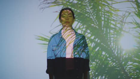 Woman-Visiting-Immersive-Art-Exhibition-With-Images-Of-Palm-Leaves-Being-Projected-Onto-Her-Face