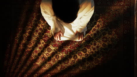 kneeling man prays for ramadan on the carpet