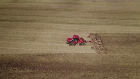 toma aérea del tractor grande en las vías tirando del sistema de grada para volver a cultivar el suelo del campo agrícola grande