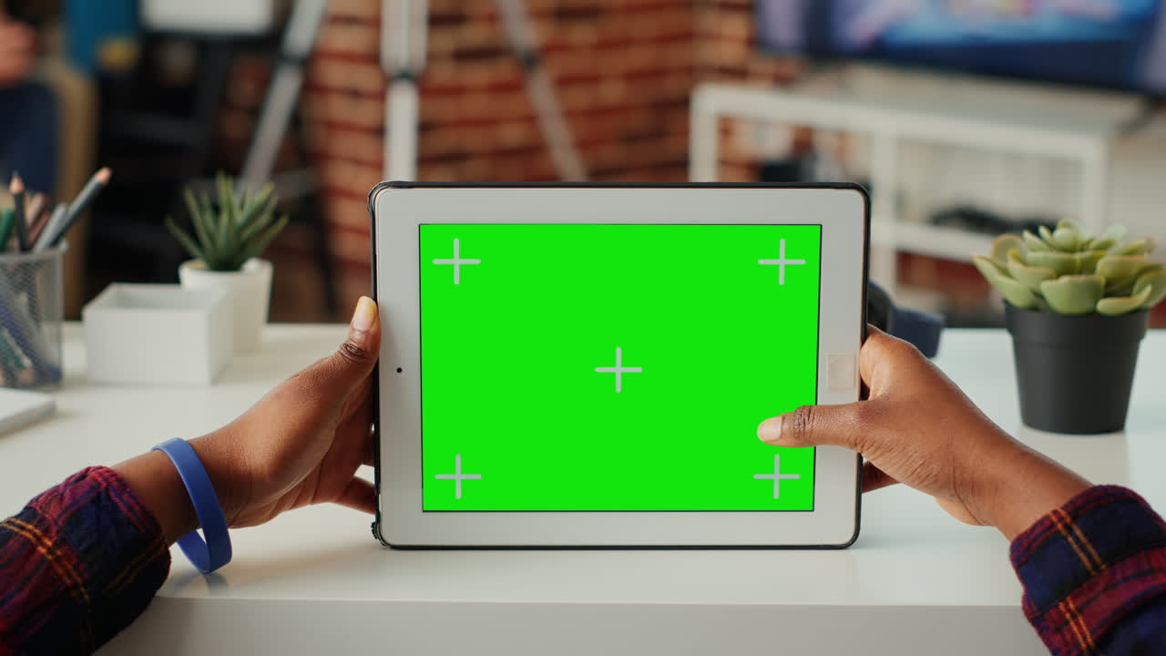 Female freelancer using horizontal greenscreen on wireless gadget