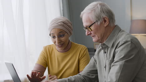 arabic woman teaching an elderly man to use a laptop 1