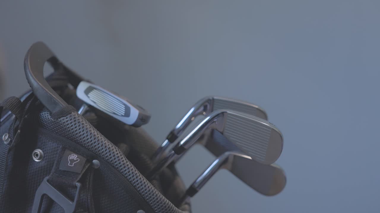 close-up shot of a hand removing a 5 iron from a golf bag to hit a shot