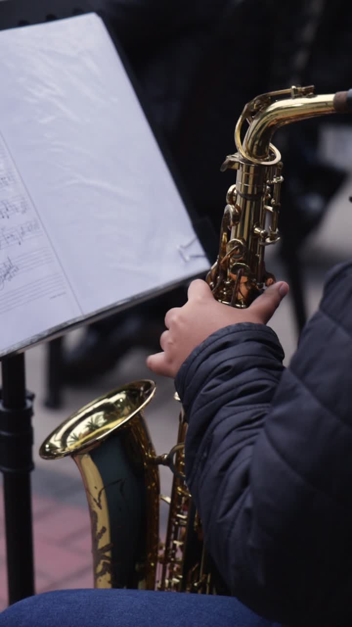 Close-Up of a Musician's Hand Playing a Golden Saxophone with Sheet Music