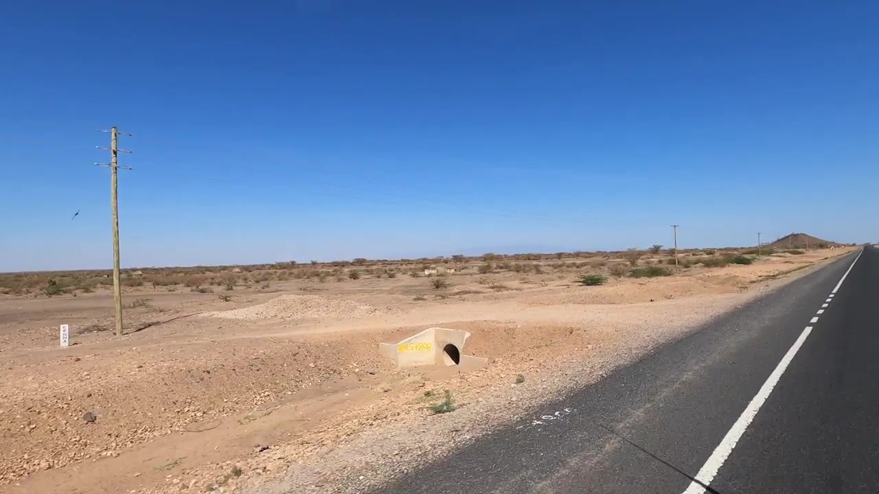 Ujęcie z jadącego pojazdu przez suchy region Turkana w północnej Kenii, z odległą pustynną drogą i otwartym krajobrazem