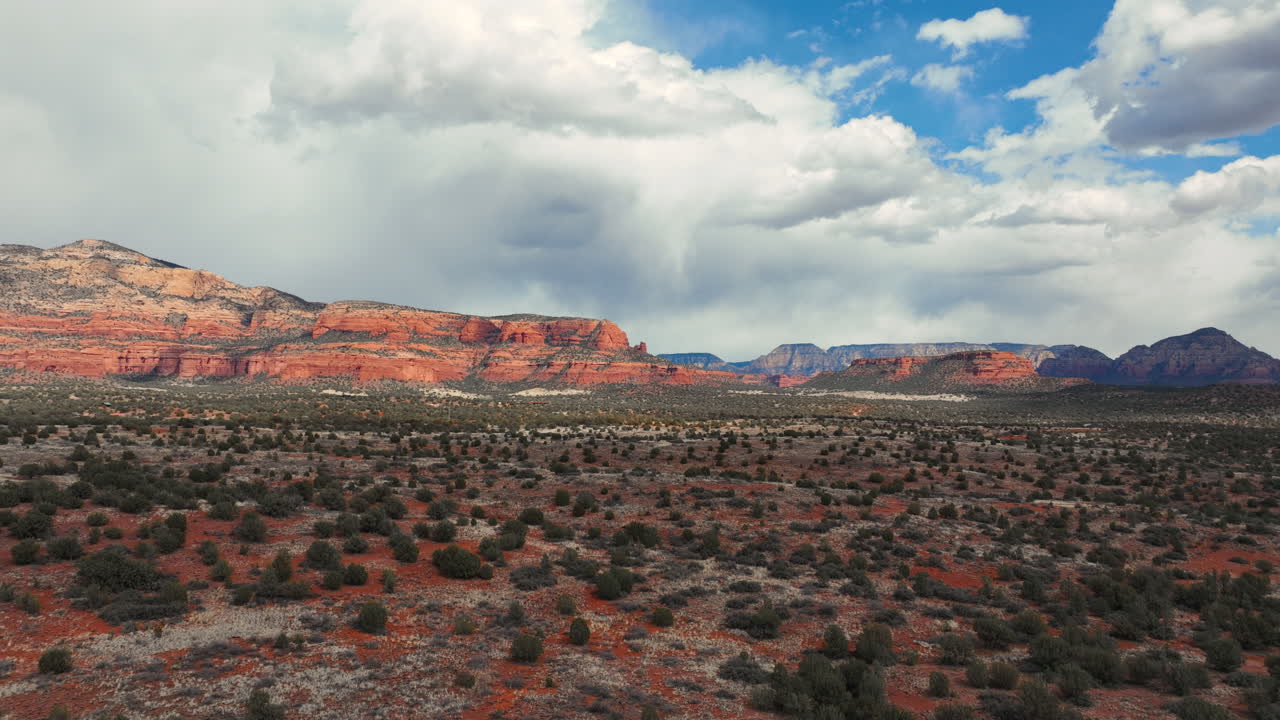 Red Rock Formations Rise Beyond the Desert Scrubland Under a Partly Cloudy Sky in Sedona, Arizona - Hyperlapse