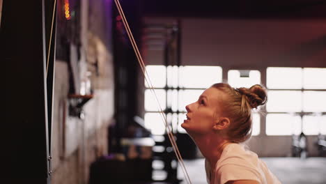 side view of young woman exercising on cable machine at fitness club