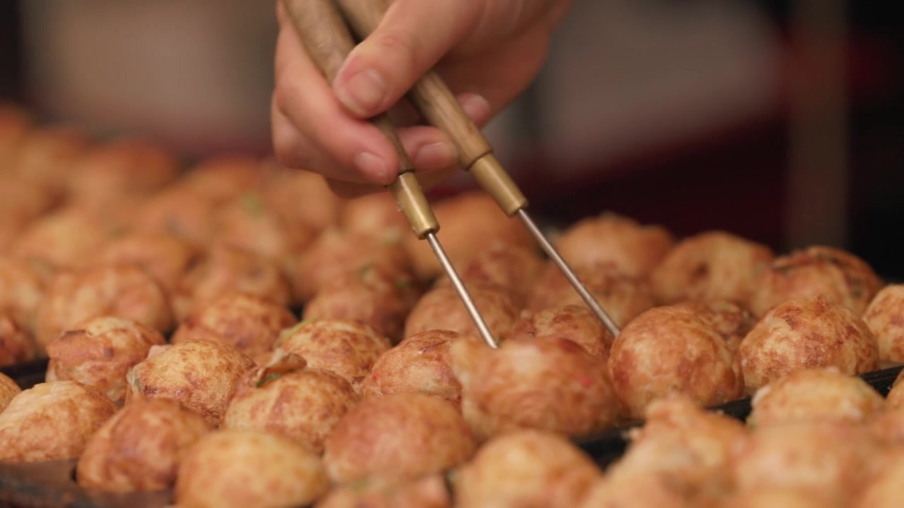 Takoyaki in cottura su una piastra calda presso una bancarella di street food - Primo piano.