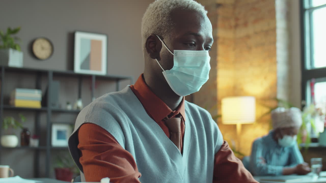 African American Businessman in Mask Working on Laptop in Office