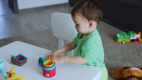 charming baby playing with bright toys at the desk. caucasian toddler is busy with toys at playroom.