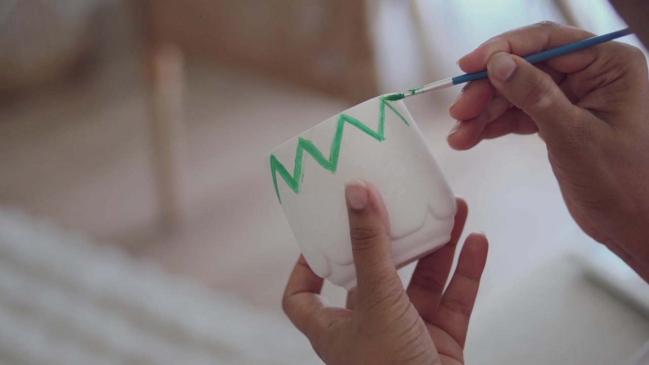Person Painting Green Zigzag Pattern on White Ceramic Pot