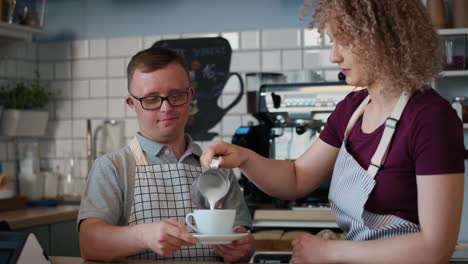 caucasian man with down syndrome helping waitress in making coffee.