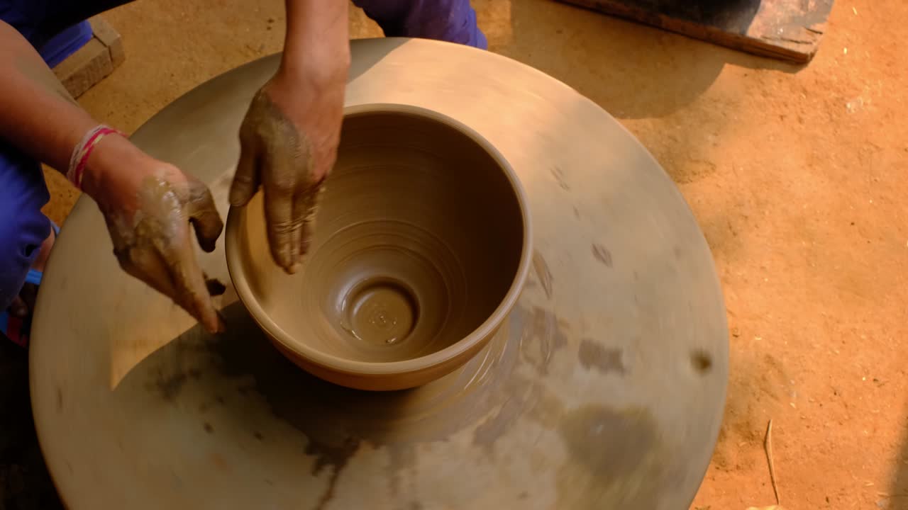 Mani esperte di un vasaio che modellano l'argilla sul tornio e scolpiscono un vaso. Shilpagram, Udaipur, Rajasthan, India