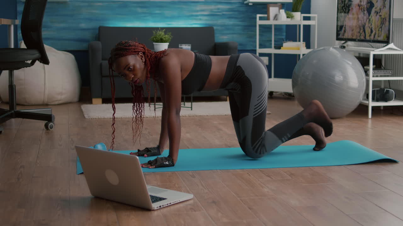 Athletic sport black woman doing morning fitness routine watching fitness workout video