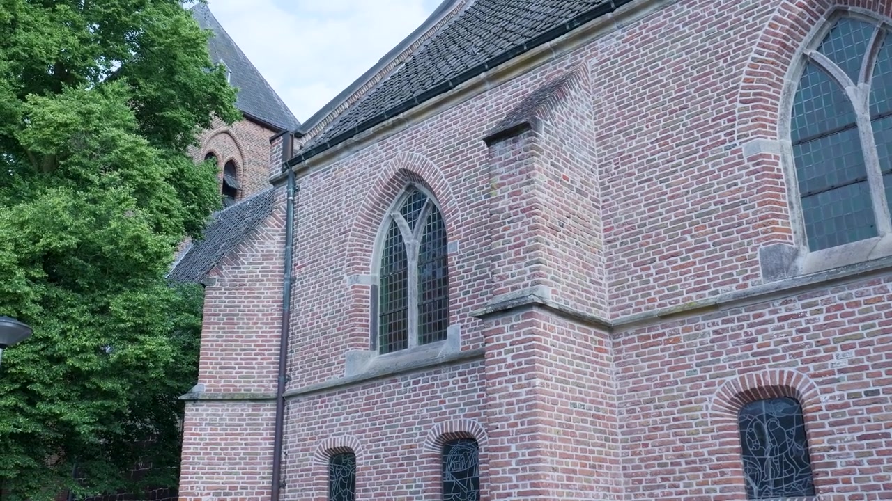Vista exterior de uma igreja histórica de tijolos com janelas góticas