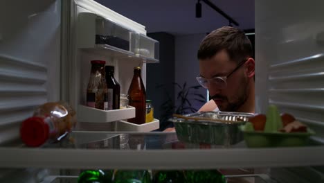 hombre comiendo pollo frito en el refrigerador por la noche