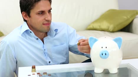 un joven lindo poniendo dinero en una alcancía