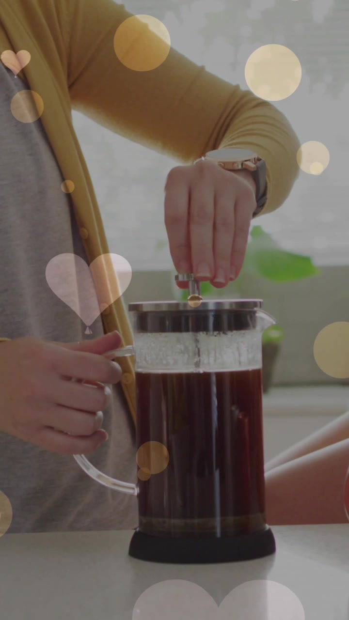 Animazione di cuori su una coppia femminile caucasica che prepara il caffè