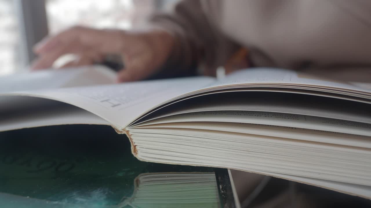 Close-up of a Hand Turning Pages of an Open Book