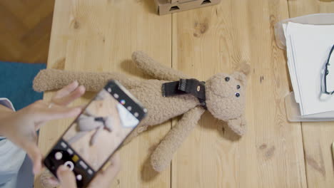 young lady taking picture of teddy bear toy