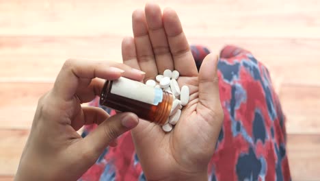 person pouring pills from a bottle into their hand