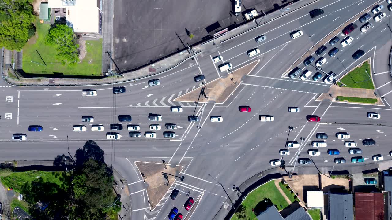 Drone aerial landscape of car vehicles travelling through traffic stoplight intersection road crossing and causeway at Erina town of Central Coast Australia transport tourism infrastructure driving