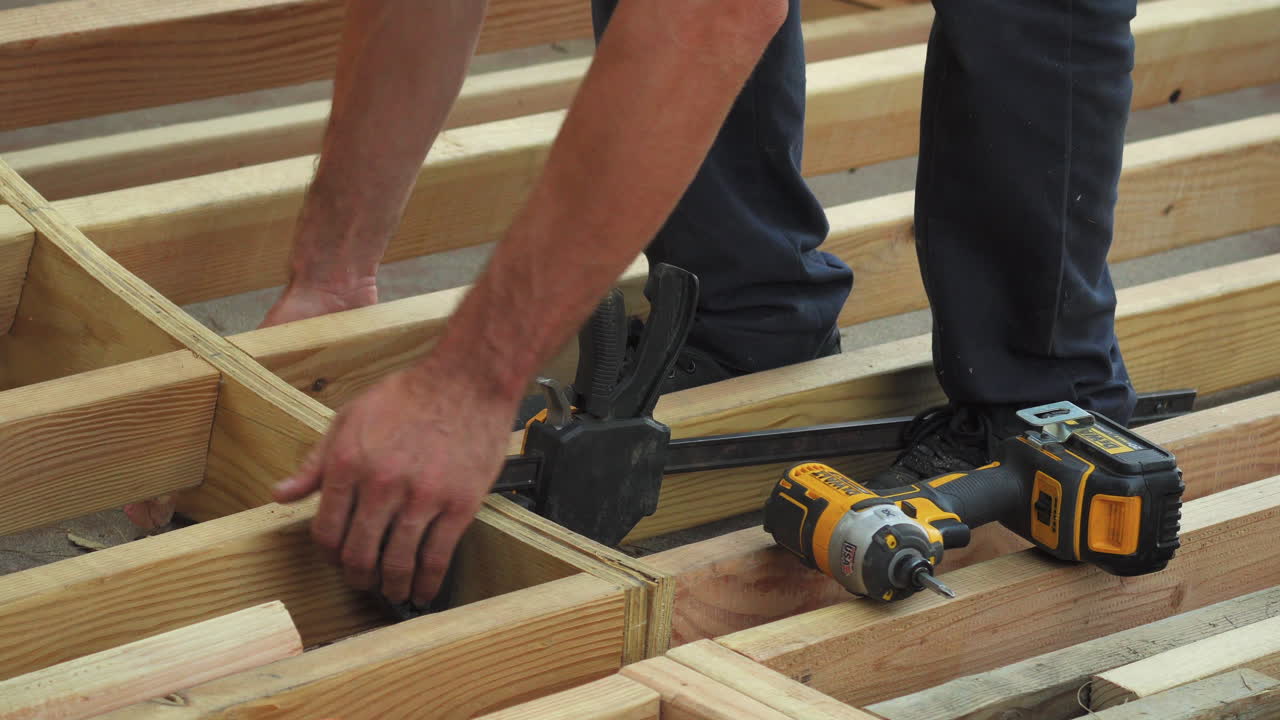 Guy building mini ramp from wood, close up of hands and tools, banging beam